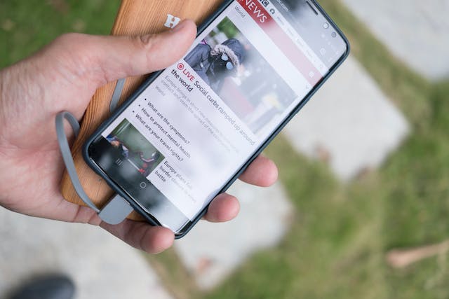Person holding smartphone showing a news website