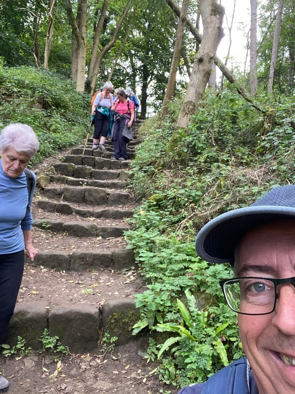 Group members carefully walk down some steps in a wooded area