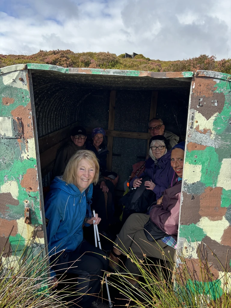 Walkers make use of a painted metal shelter to stay out of the wind and rain