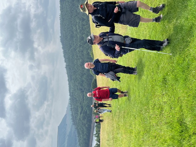 The group are spread out climbing a gentle hill away from the reservoir.
											It's still quite cloudy but there is a little sunlight.